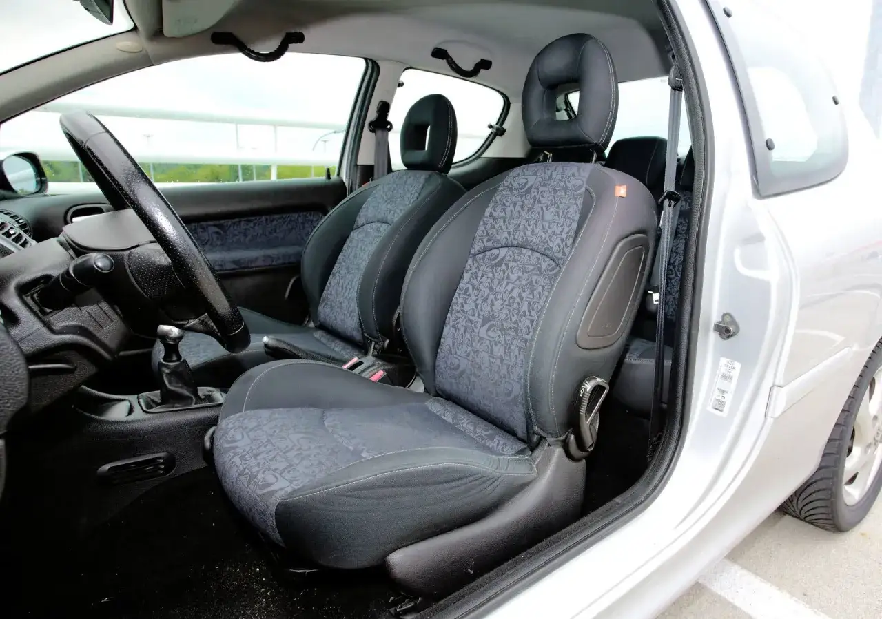 Wnętrze Peugeot 206 SW: przednie fotele z tapicerką, kierownica, dźwignia zmiany biegów.