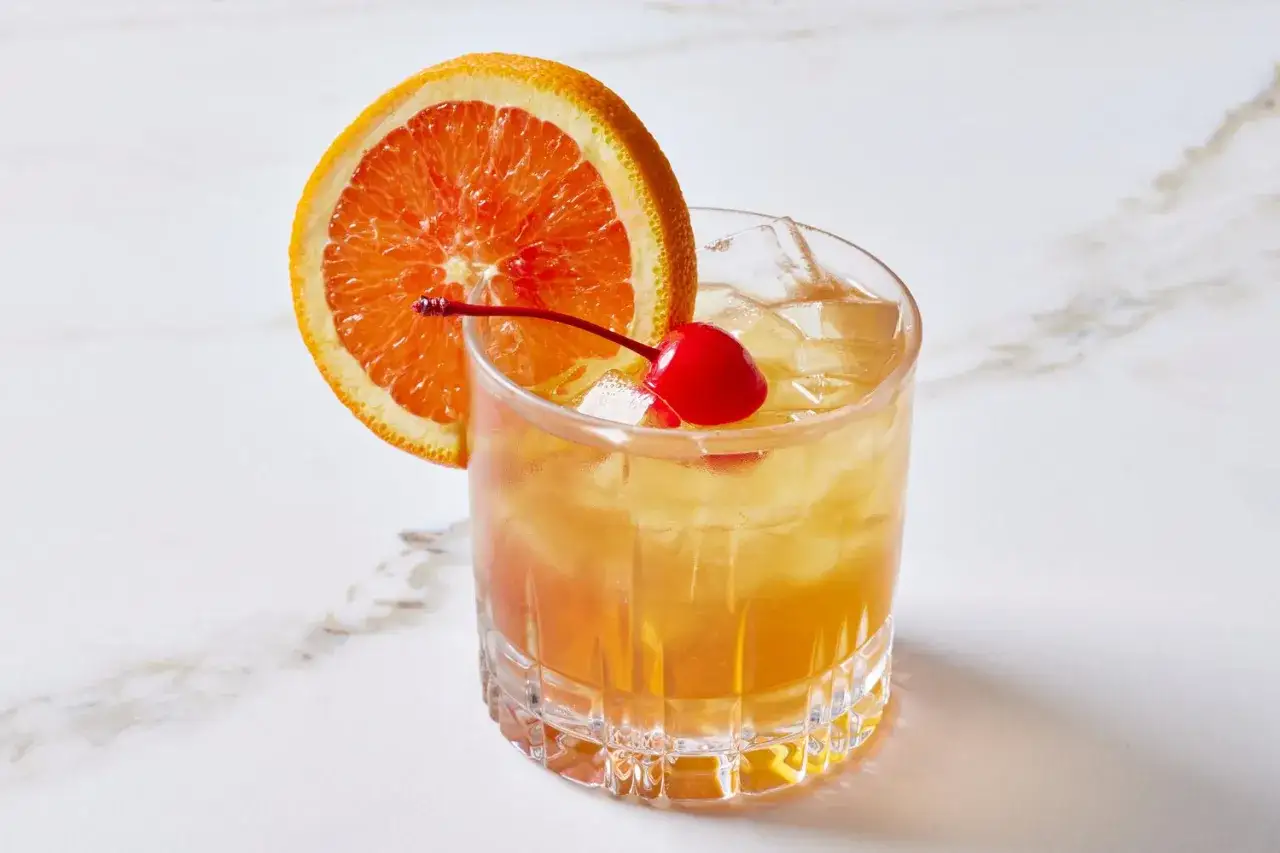 En amaretto sour med apelsinskiva och körsbär.