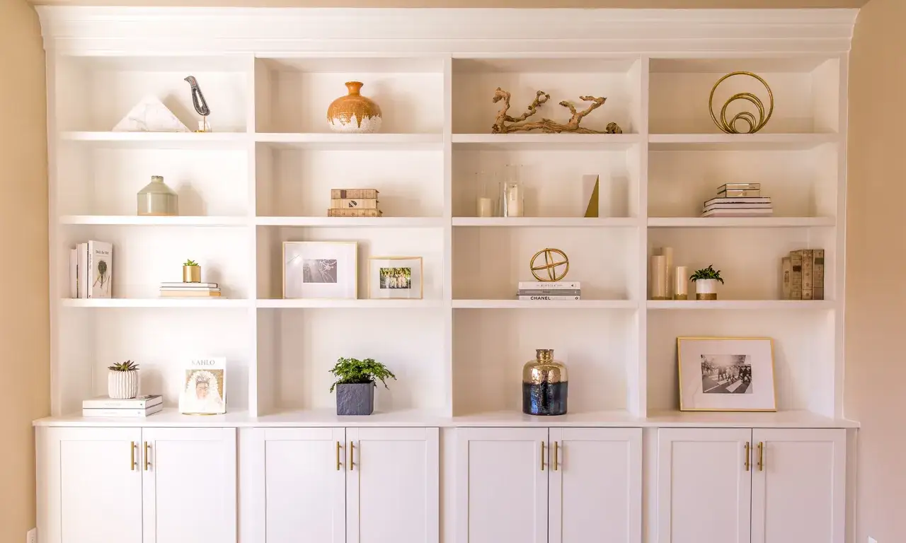 A beautifully styled built-in shelving unit showcases decorative objects, books, and framed photos.