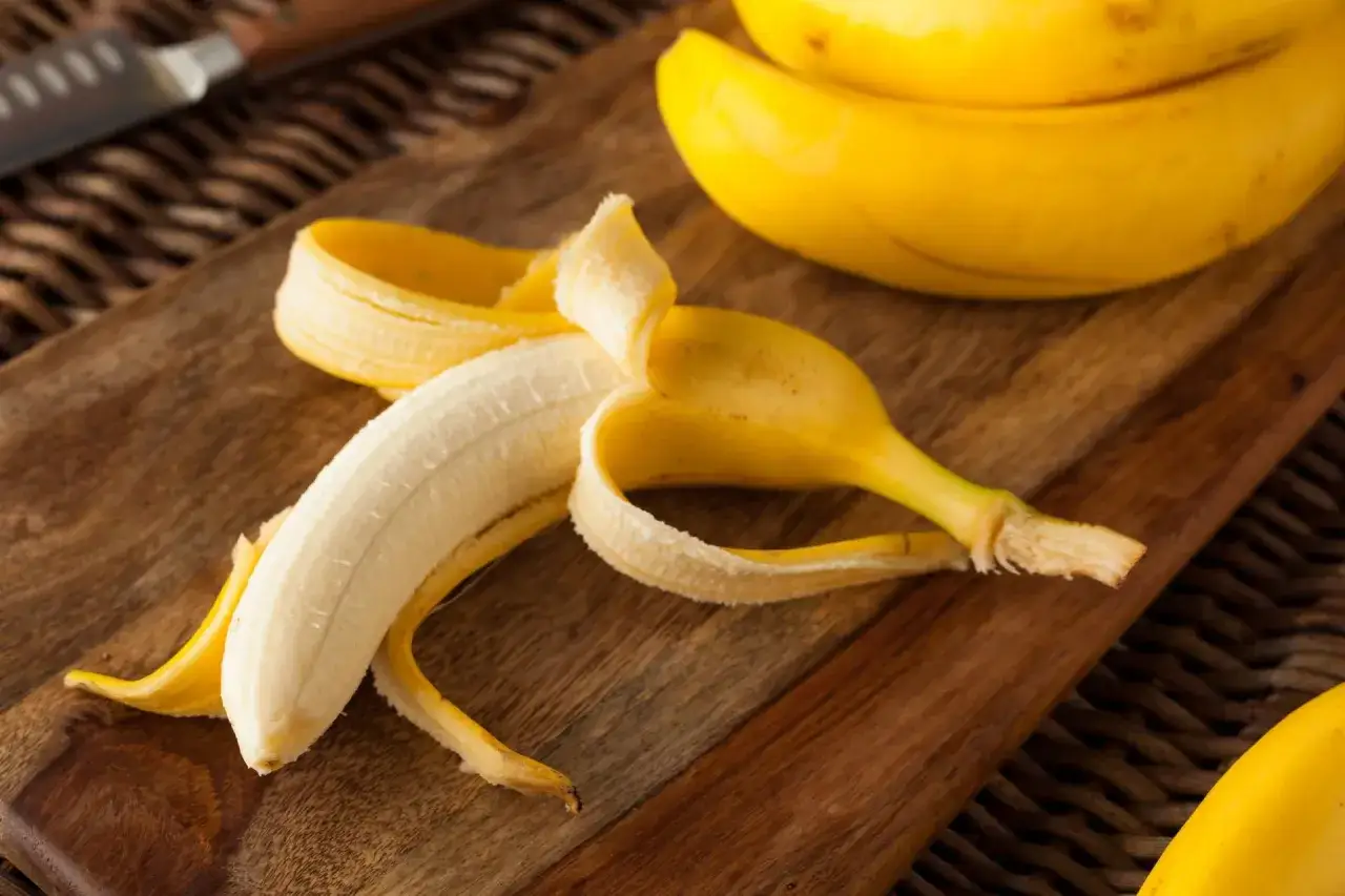 Połówka obranego banana na drewnianej desce. Idealny banan na pusty żołądek, gdy potrzebujesz szybkiej energii.