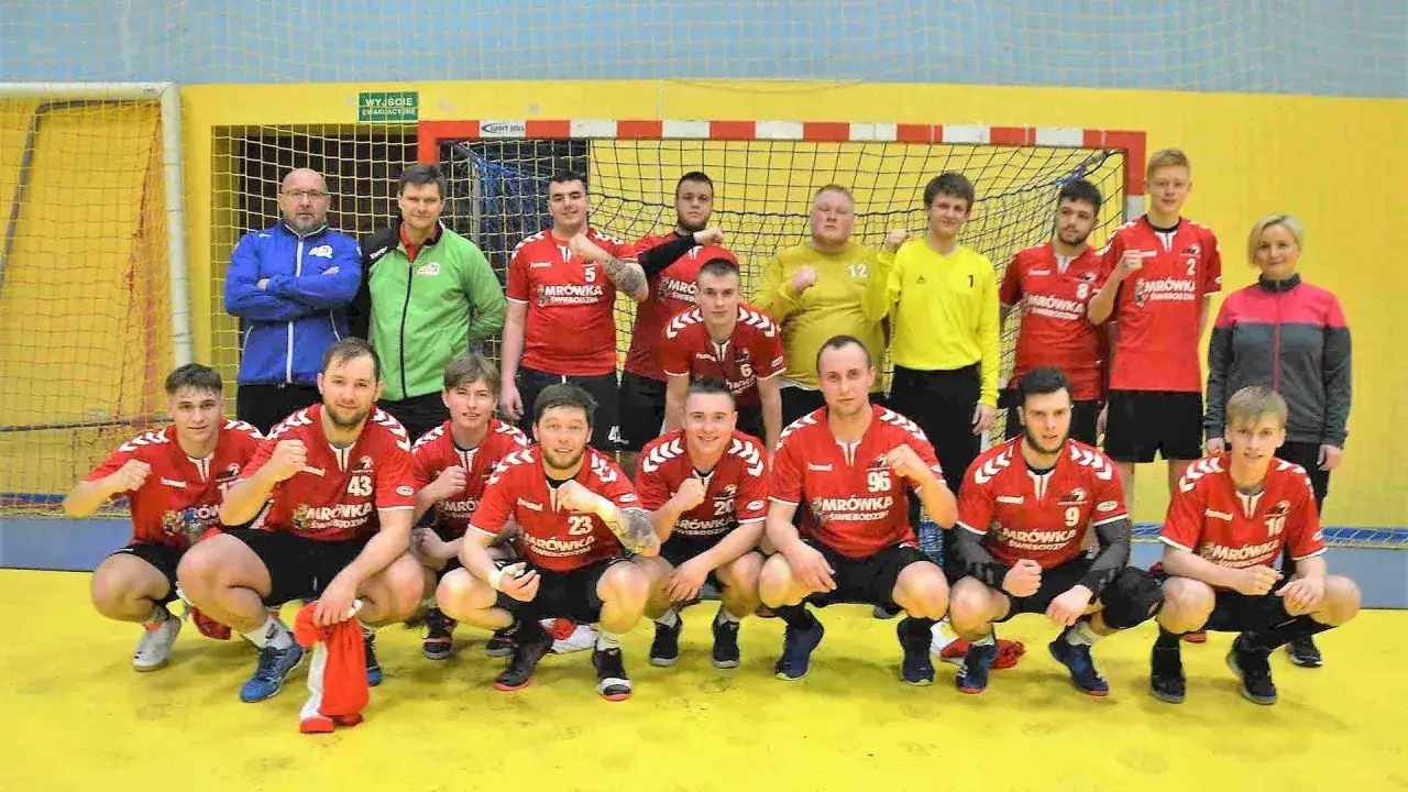 Drużyna piłki ręcznej z Przemysławem Kochem w czerwonych strojach pozuje do zdjęcia.