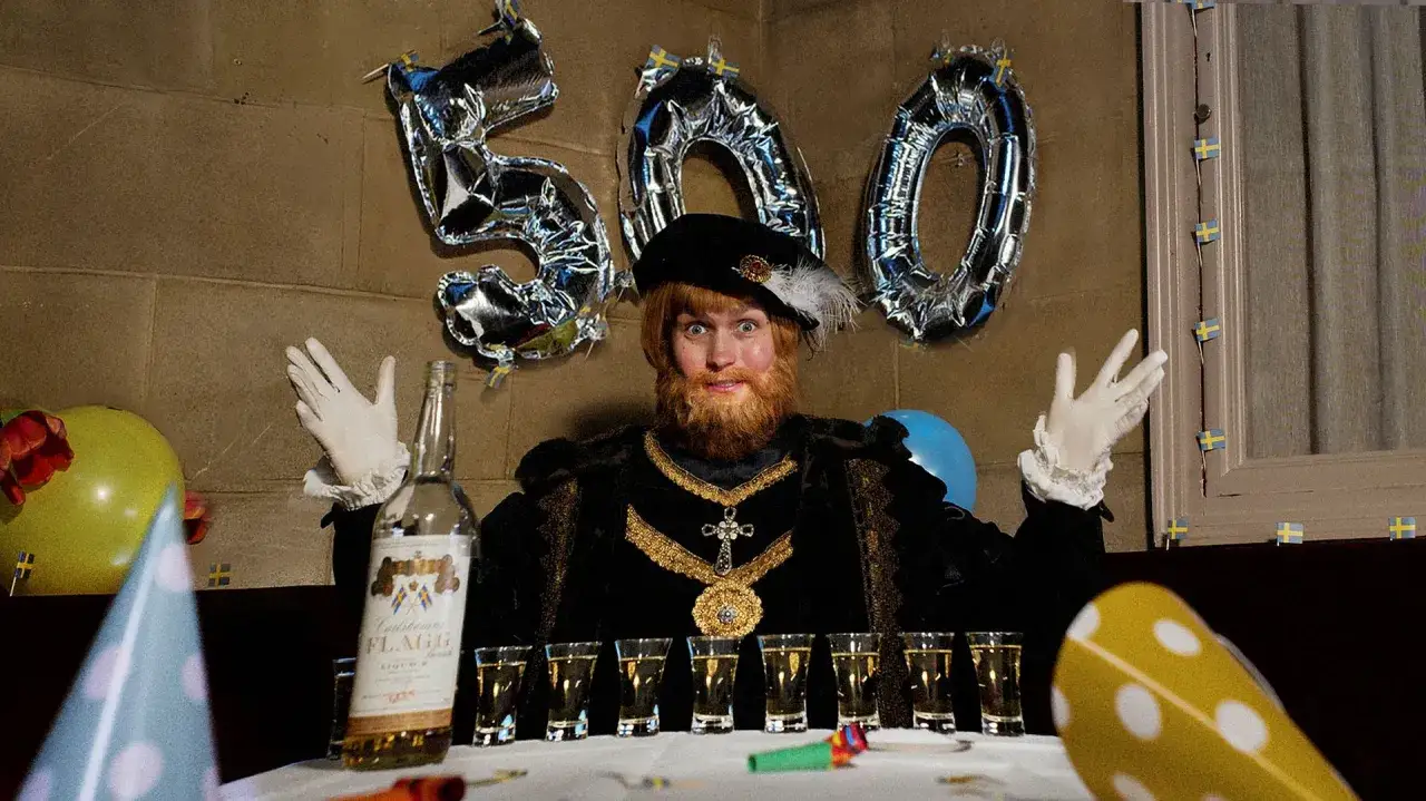 Gustav Vasa the musical firar 500 år med shotglas och ballonger. En skäggig man i historisk dräkt poserar glatt.
