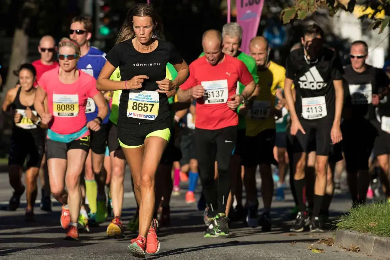 Löpare i Stockholm Halvmarathon, nummer 8657 i förgrunden, kämpar på för att klara halvmaraton distans.