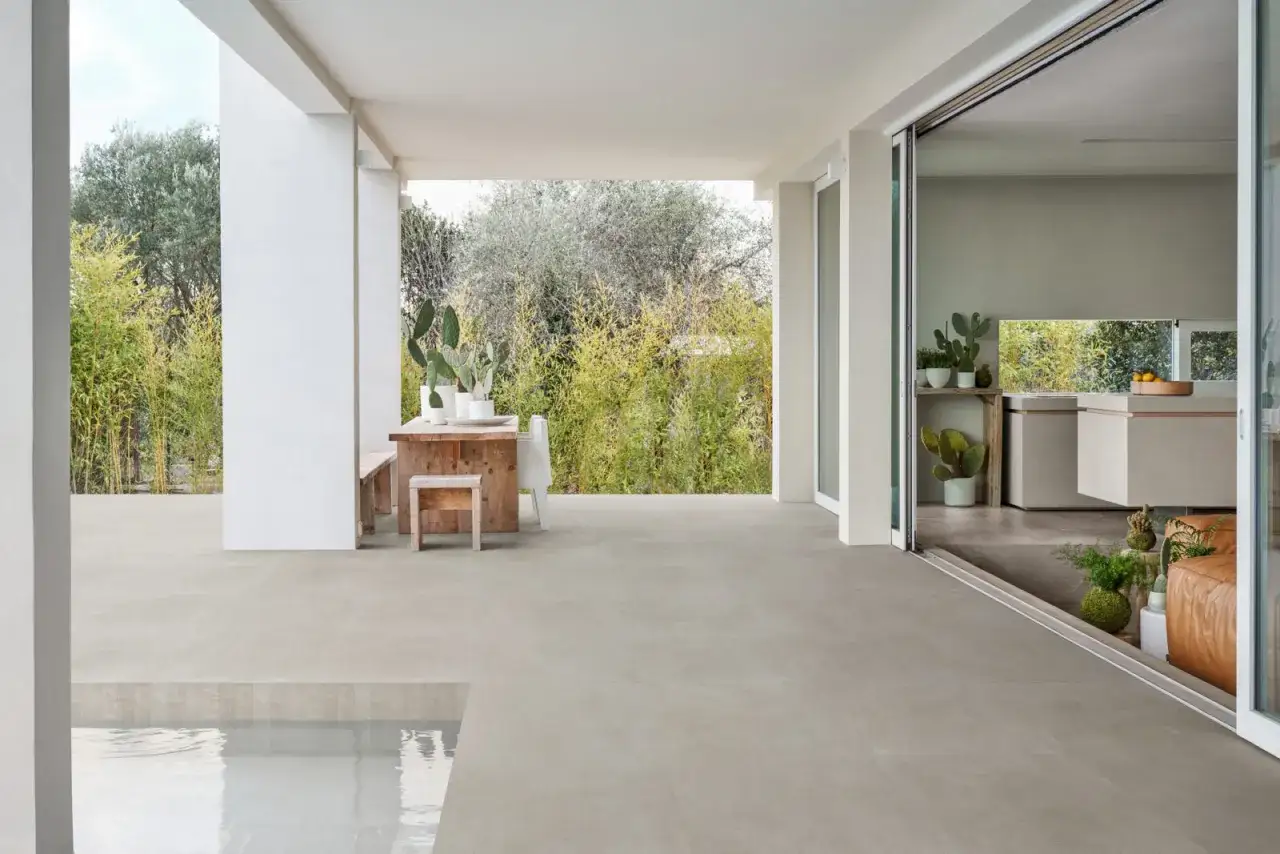 Terraza moderna con suelo de porcel&aacute;nico que es perfecto para exteriores, mesa de madera y piscina.