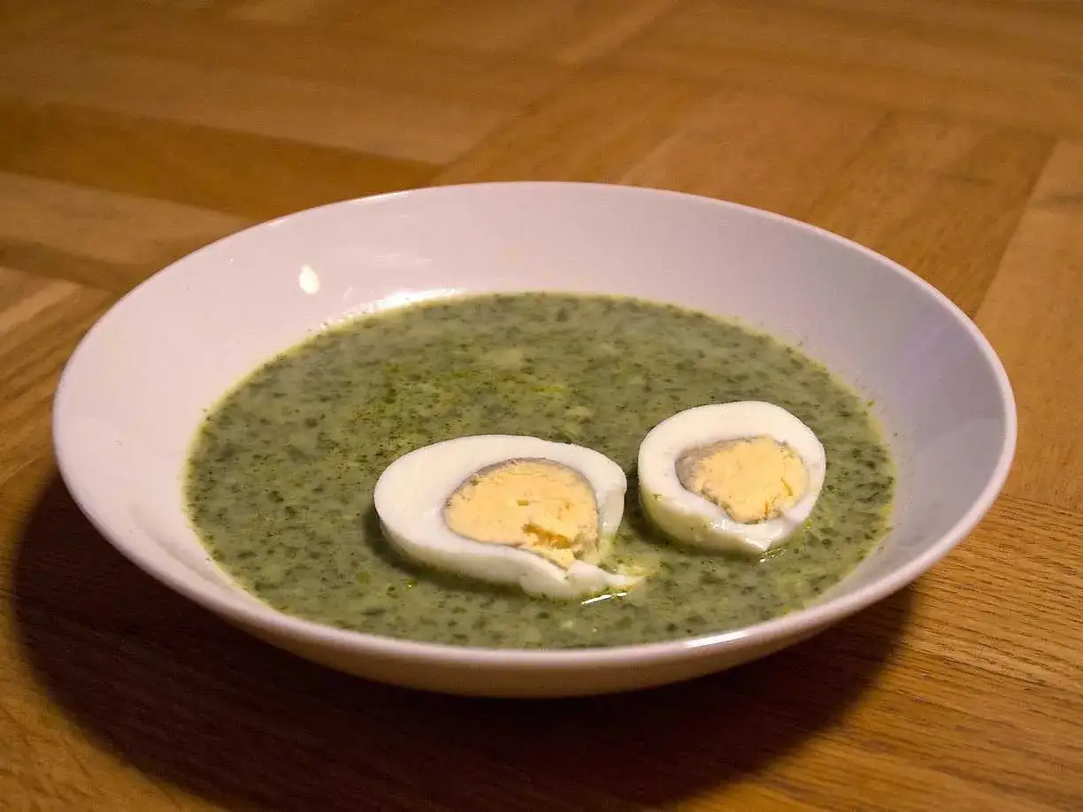 En skål med grön spenatsoppa med två halvor av hårdkokt ägg. Ett klassiskt spenatsoppa recept som är både nyttigt och gott.