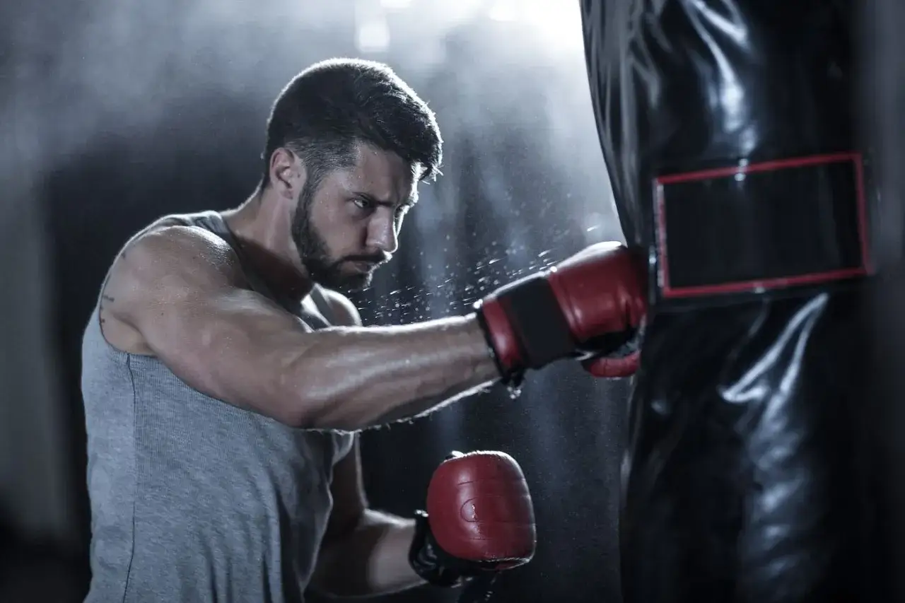 A determined boxer pounds a heavy bag, sweat flying. This intense workout shows how boxing can help with anger management.