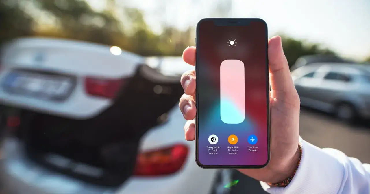 Dłoń trzyma iPhone'a z włączonym trybem Night Shift, gotowego na nocną zmianę.
