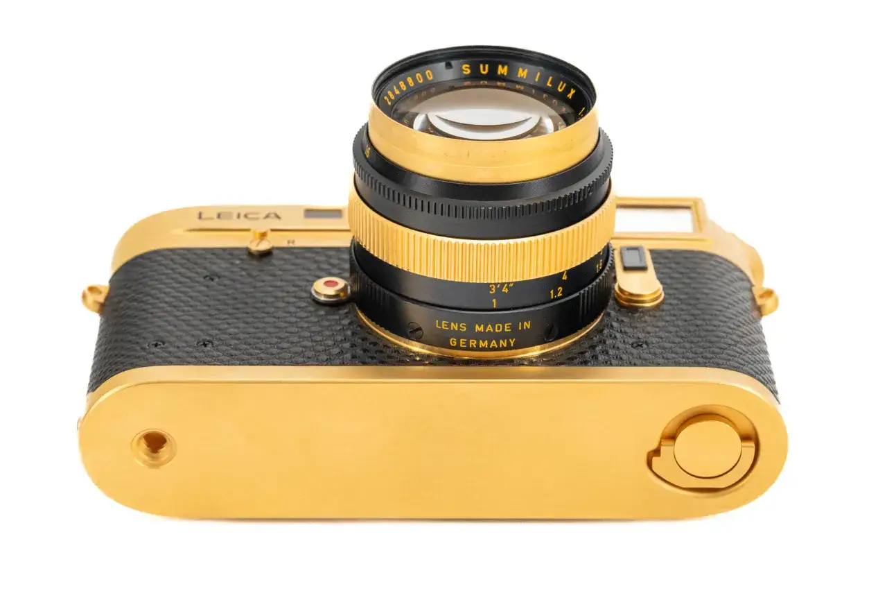 A gold and black Leica M4 camera with a Summilux lens attached. This classic camera, paired with its lenses, is a photographer's dream.