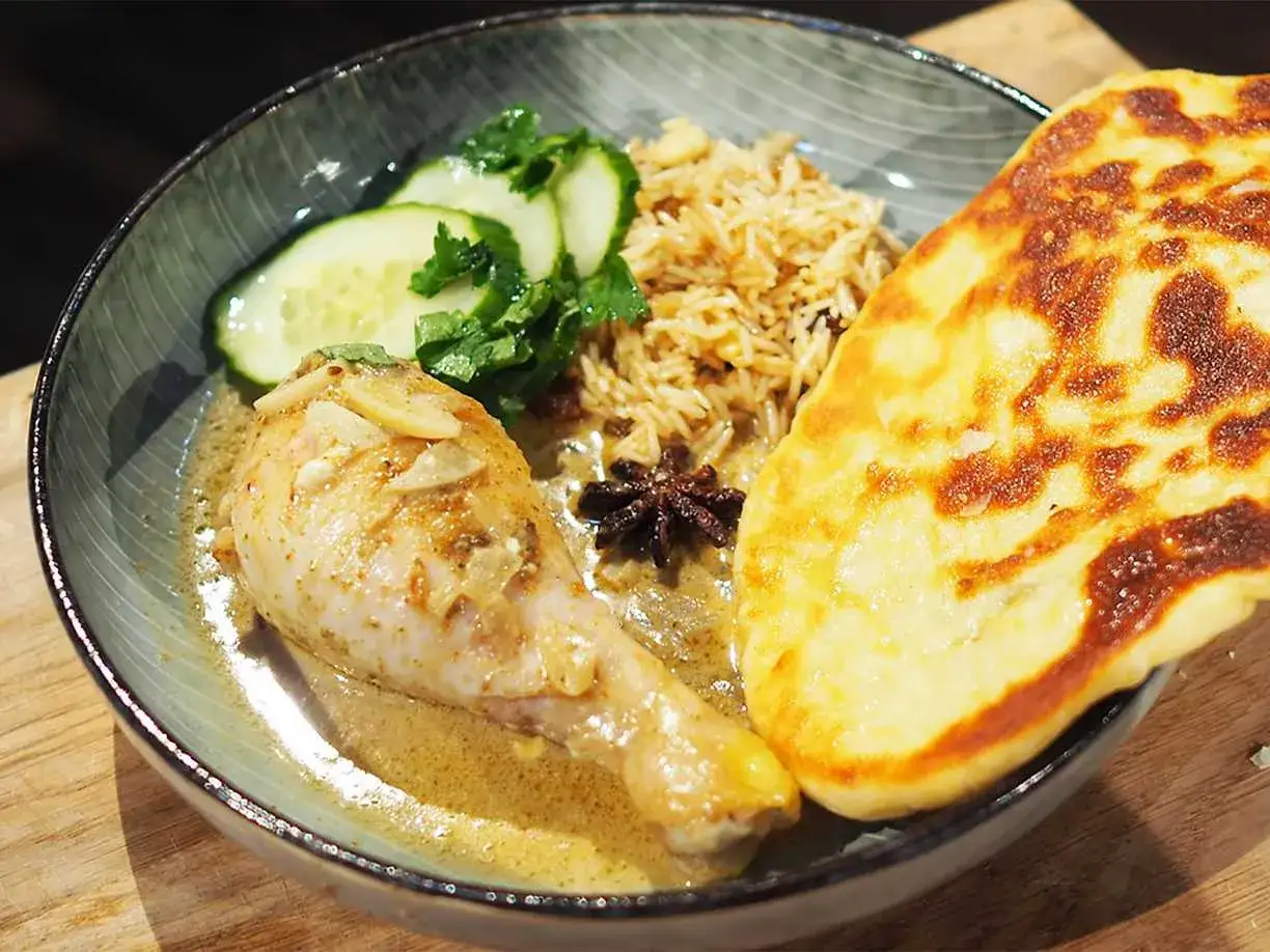 En l&auml;cker kycklingklubba i kr&auml;mig s&aring;s, serverad med ris, gurka och naanbr&ouml;d. En h&auml;rlig butter chicken-upplevelse.