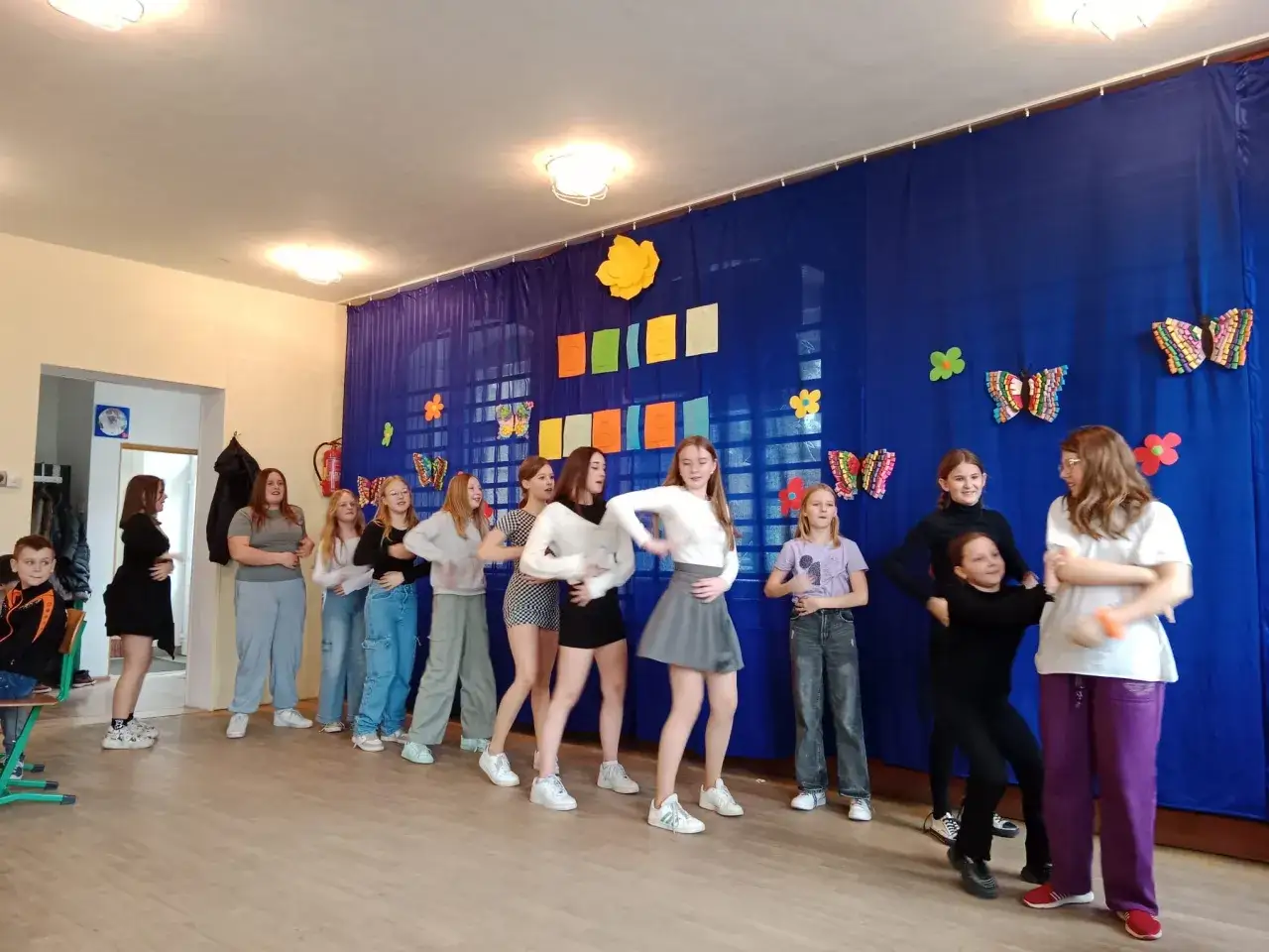 Dziewczyny tańczą na szkolnej scenie, przygotowując się do Dnia Kobiet. Pomysły na występ są świetne!