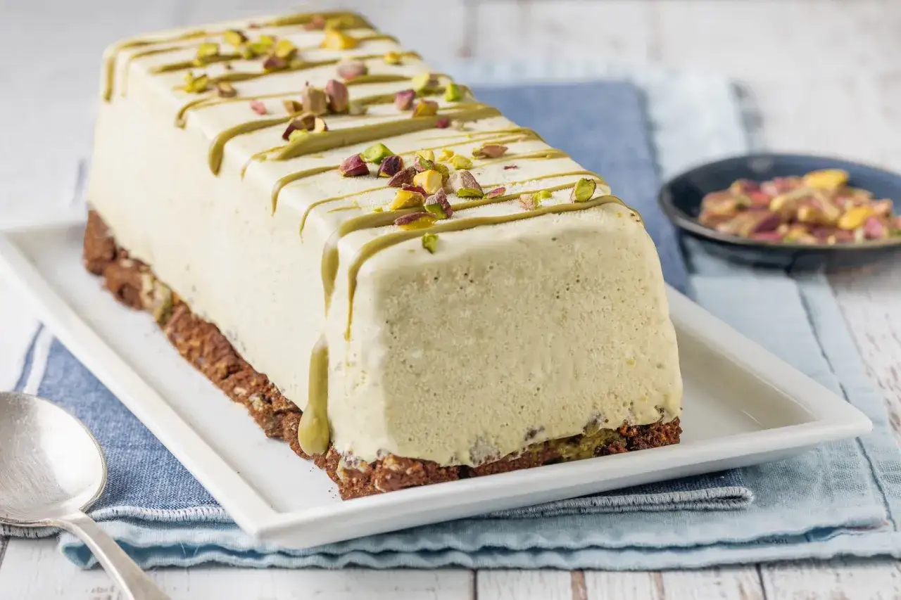 Delizioso semifreddo al pistacchio, decorato con glassa verde e granella di pistacchi, su una base croccante.