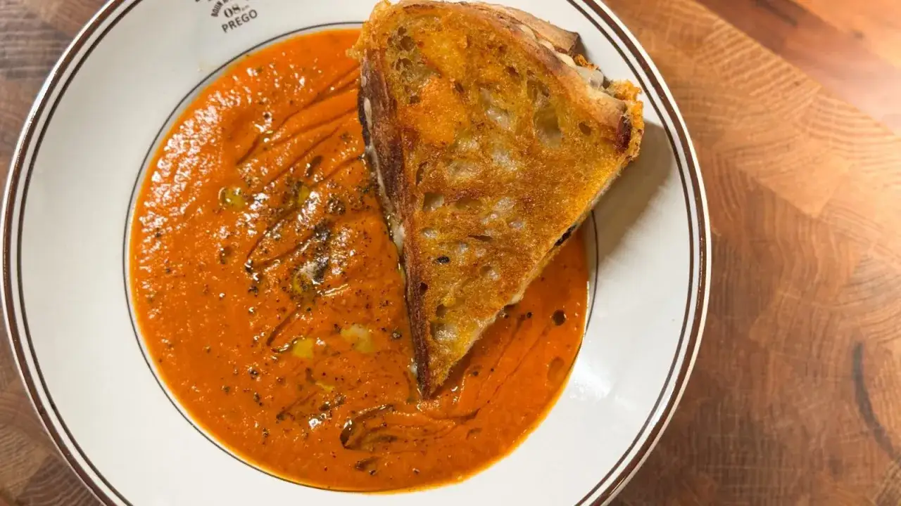 En krämig tomatsoppa med en gyllene grillad ostmacka, perfekt som vin till tomatsoppa.