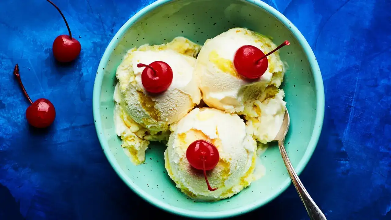 Schüssel mit cremigem Eis, garniert mit Kirschen. Ein Löffel liegt bereit, um dieses köstliche Eis mit Alkohol zu genießen.