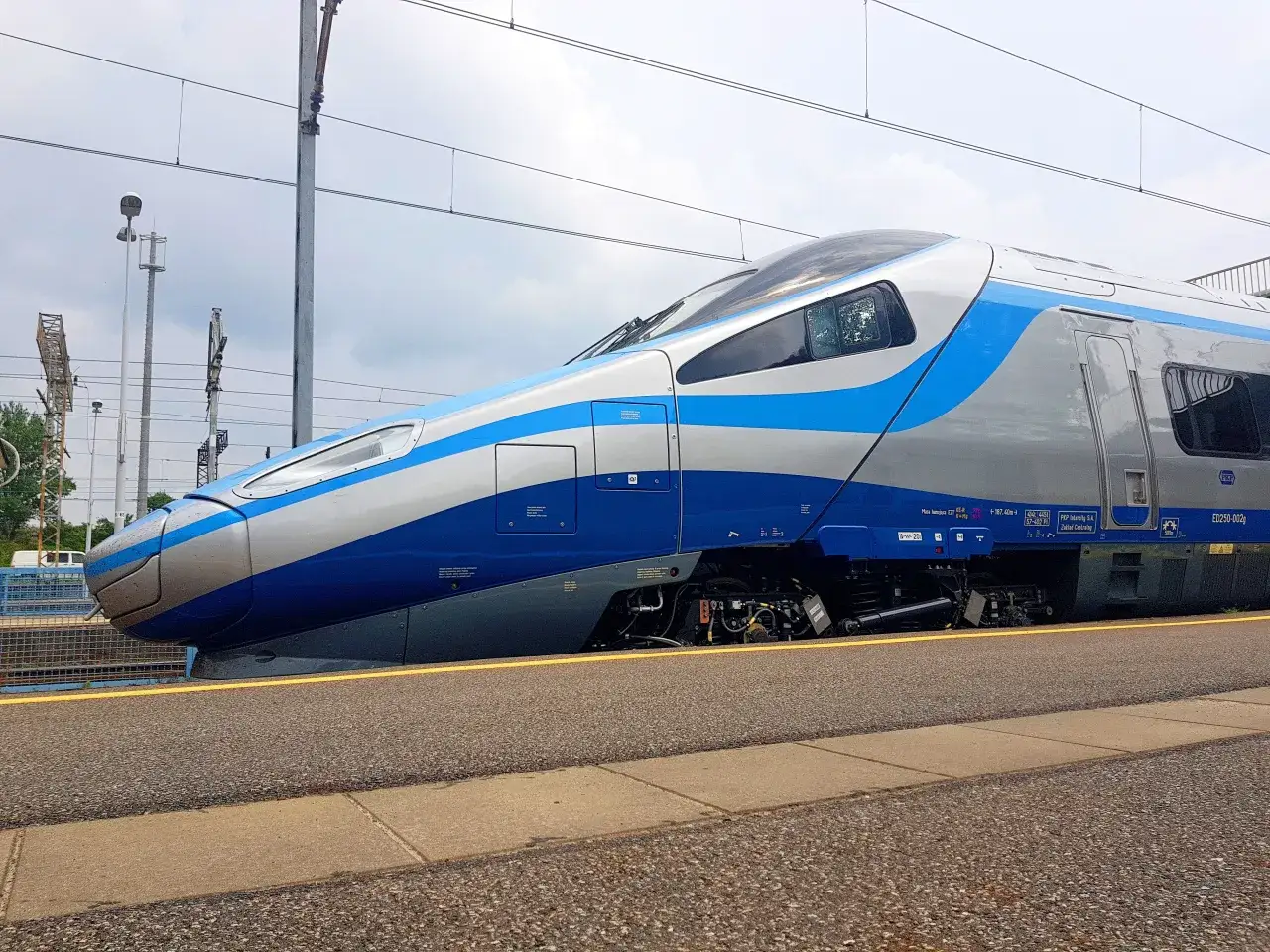 Srebrno-niebieskie Pendolino ED250-002g stoi na peronie.