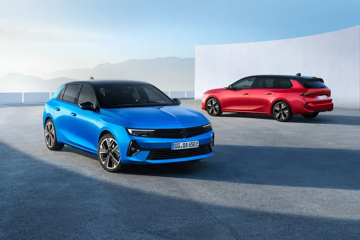 Niebieski i czerwony Opel Astra 2025 na tle nowoczesnej architektury i górskiego krajobrazu.