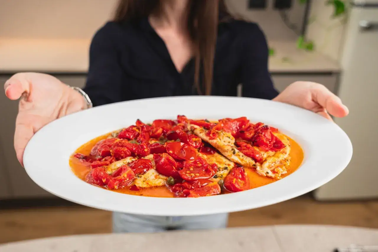 Un invitante piatto di pollo alla pizzaiola, con succosi pomodorini e capperi, pronto per essere gustato.