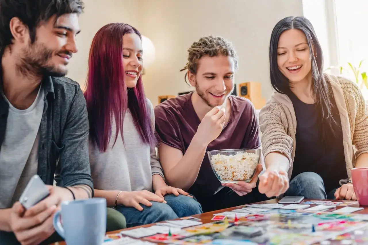 Amici che giocano a uno dei 10 giochi da tavolo per famiglie più popolari, con popcorn e risate.