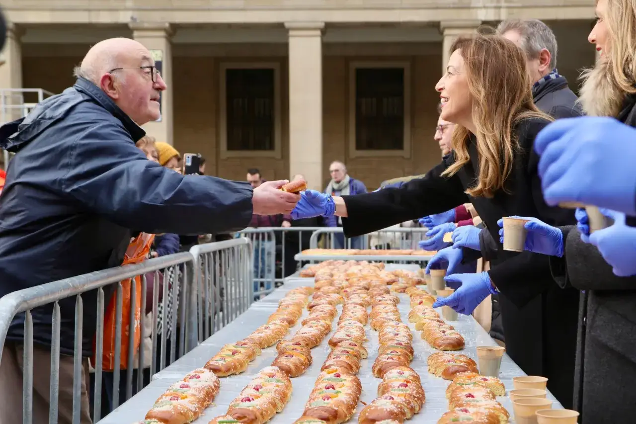 Reparto de dulces cuando es San Valero. Hombres y mujeres con guantes azules ofrecen y reciben dulces de una larga mesa.