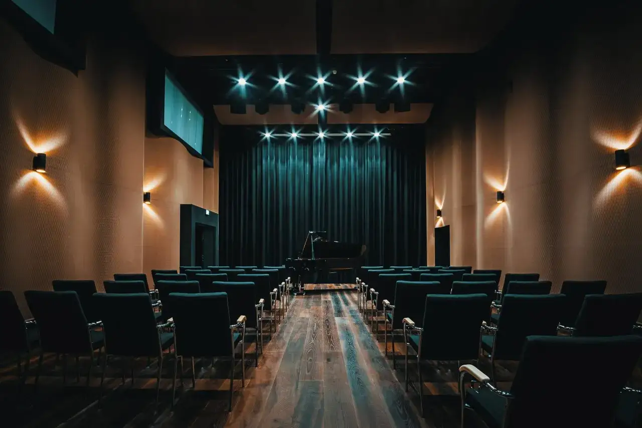 Pusta sala koncertowa z fortepianem na scenie, gotowa na recital.