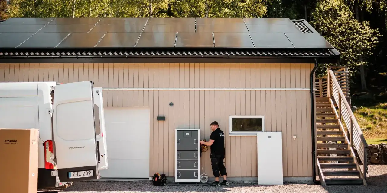 Installation av en batteribank hemma med solpaneler p&aring; taket. En tekniker kopplar in utrustning vid husv&auml;ggen.