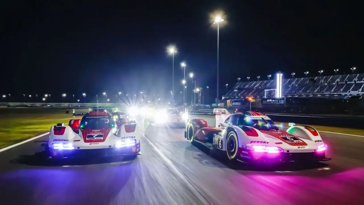 Porsche-Rennwagen rasen bei Nacht &uuml;ber die Strecke, die Lichter von Le Mans spiegeln sich im Asphalt.
