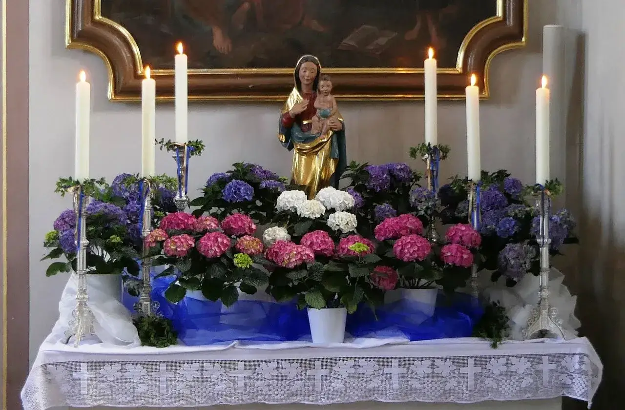 Festliche Marienstatue mit Hortensien und Kerzenlicht. Eine wundersch&ouml;ne Marienandacht im Mai, die Ruhe und Besinnlichkeit ausstrahlt.