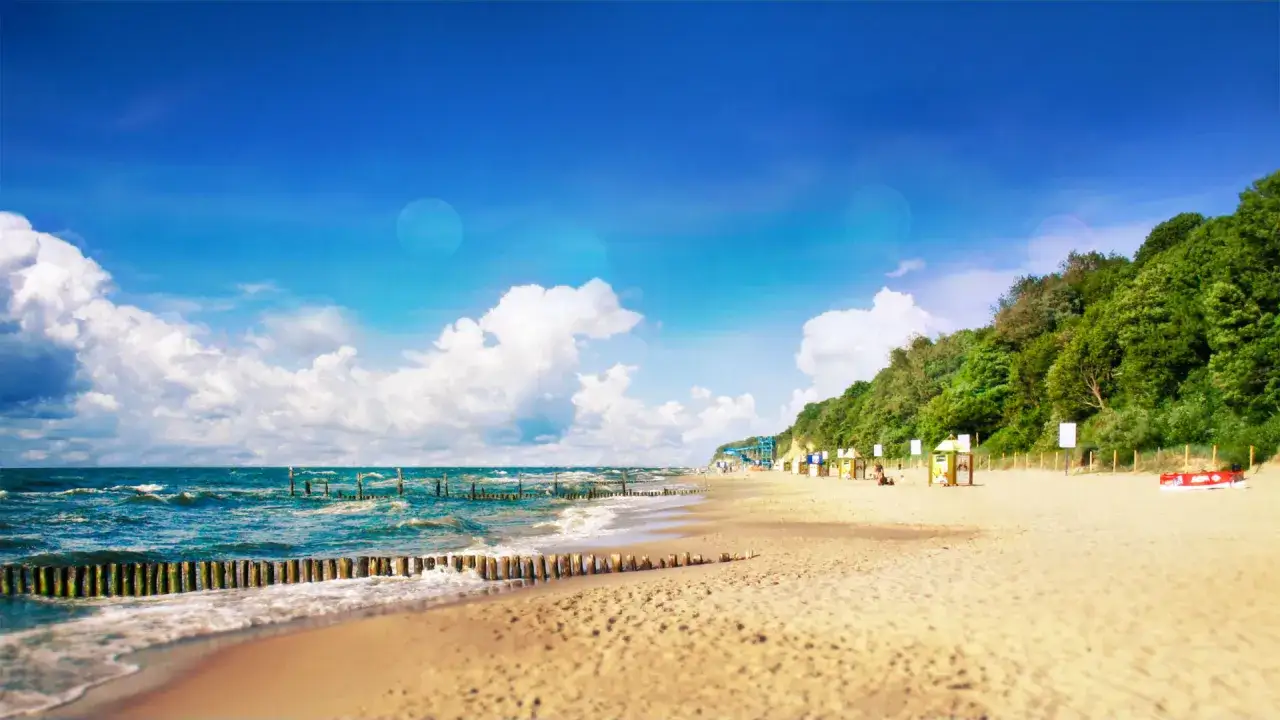 Piękna plaża w Pobierowie, idealne miejsce na wakacyjny wypoczynek. Błękitne niebo, szum fal i zielone wzgórza tworzą rajski krajobraz.