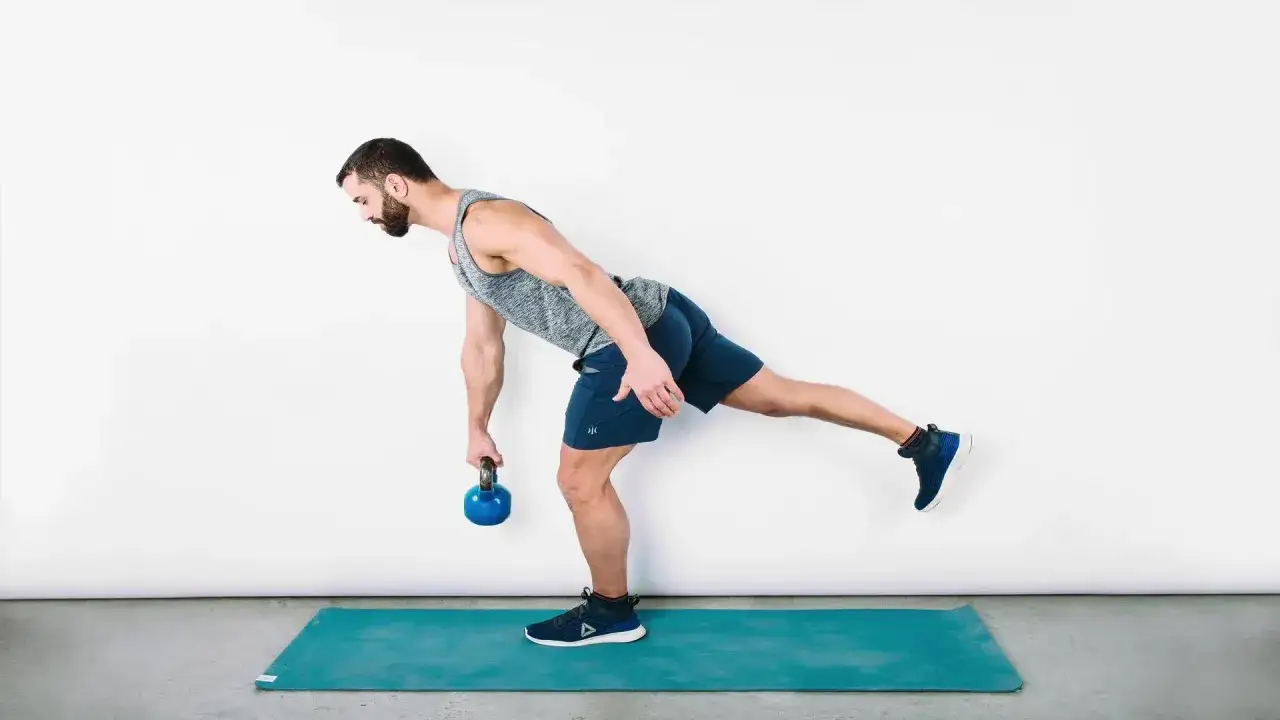 Uomo esegue stacchi rumeni su una gamba con kettlebell, un ottimo esercizio per rinforzare le ginocchia e migliorare l'equilibrio.