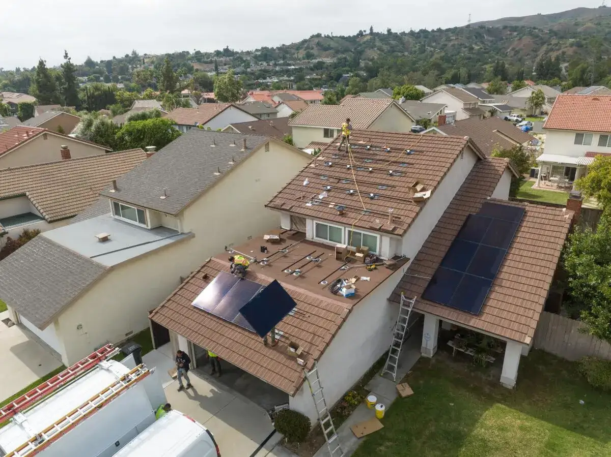 Instalación de placas solares en tejados de una comunidad de vecinos. Técnicos trabajan en la colocación de paneles, resolviendo problemas de instalación.
