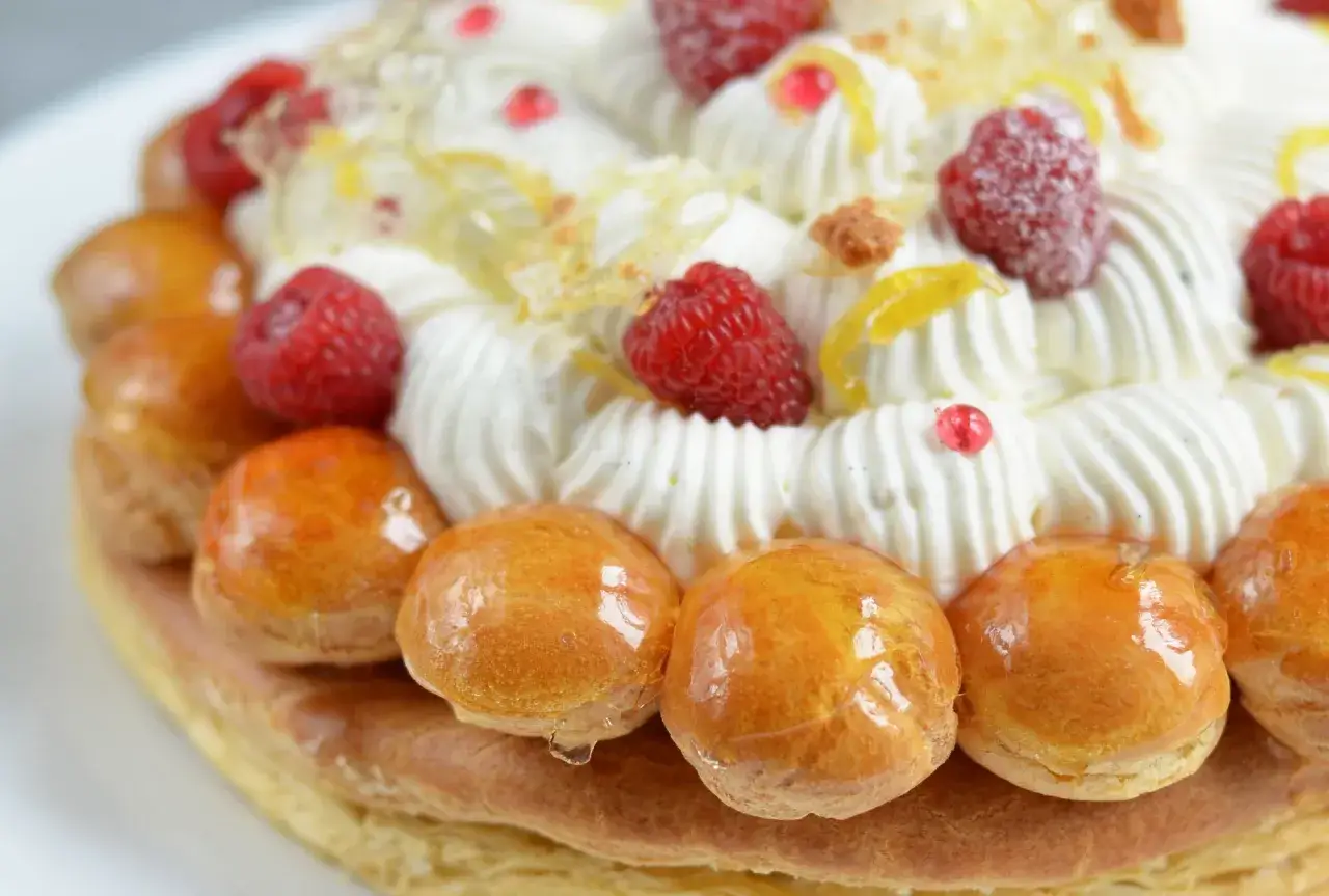 Un d&eacute;licieux saint honor&eacute; framboise, garni de cr&egrave;me fouett&eacute;e, de fruits rouges et de petites brioches caram&eacute;lis&eacute;es.