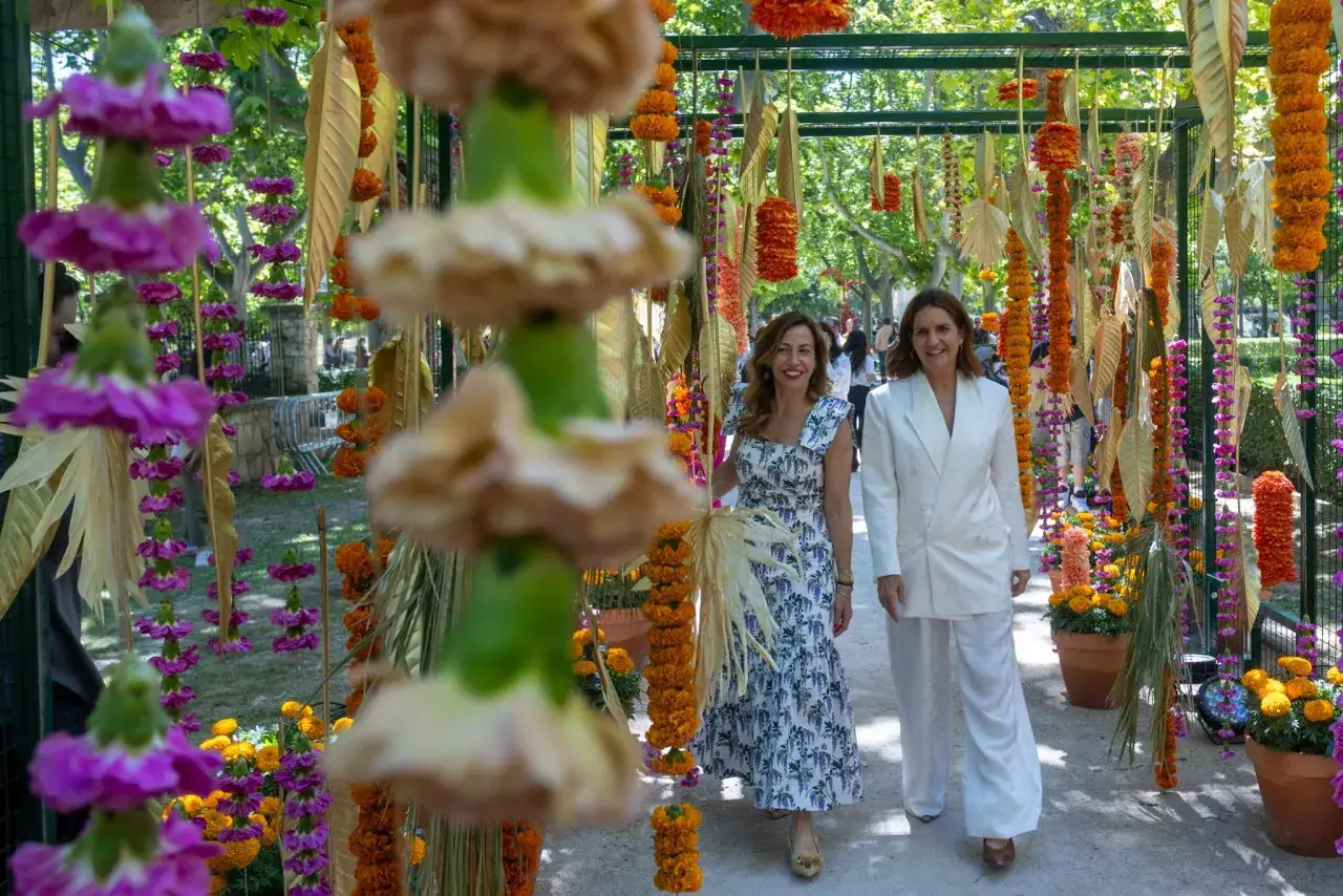 Dos mujeres pasean entre coloridas decoraciones florales. ¡Zgz florece con esta vibrante exhibición!