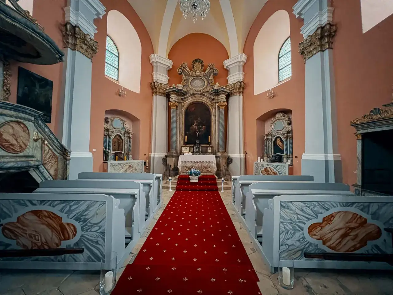 Wnętrze kaplicy św. Anny w Karpaczu z czerwonym dywanem prowadzącym do ołtarza.