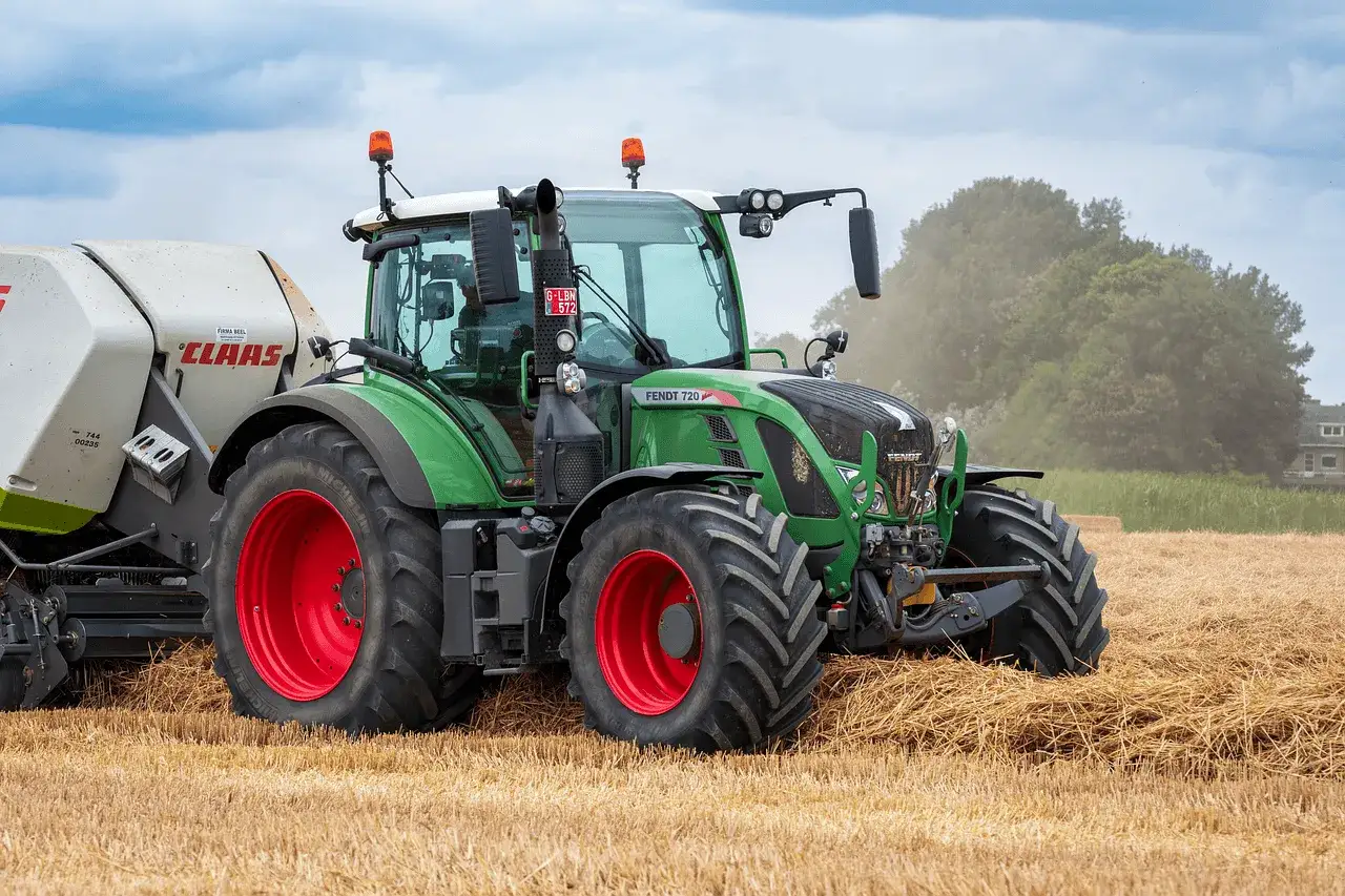Zielony traktor Fendt z przyczepą Claas pracuje na polu, zbierając słomę. To pokazuje, co opłaca się uprawiać.