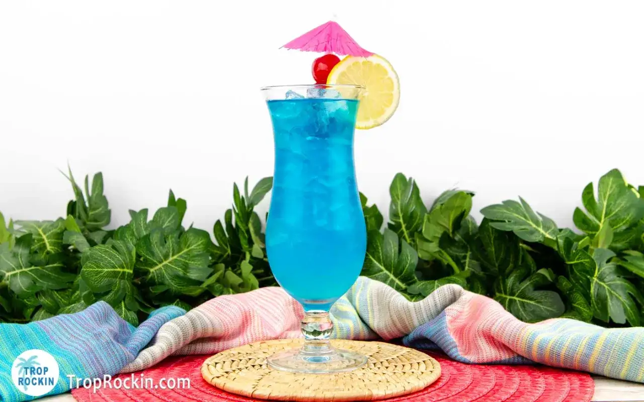 Orzeźwiający drink z blue curacao, ozdobiony cytryną i wisienką, idealny na tropikalne wakacje.