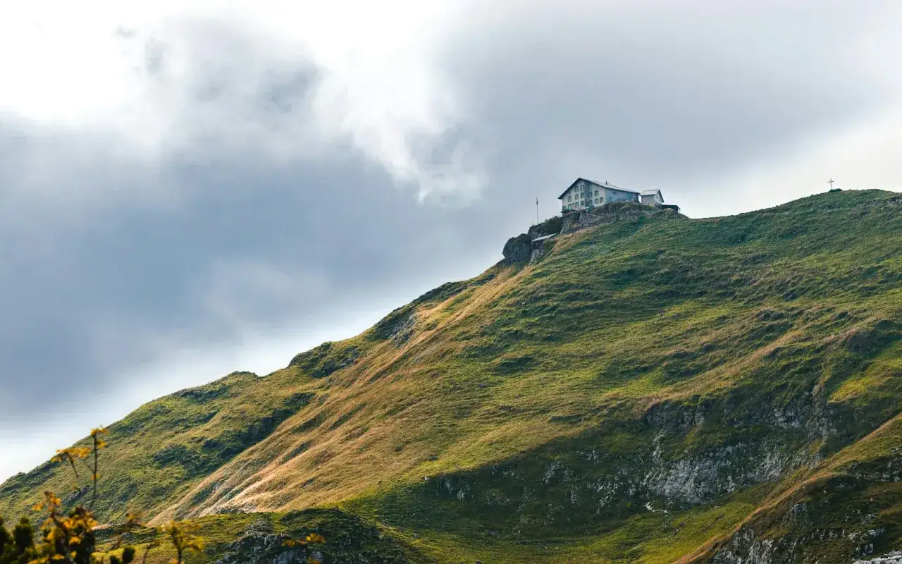 Rifugio GR10 sui Pirenei, un edificio su un crinale erboso sotto un cielo nuvoloso.