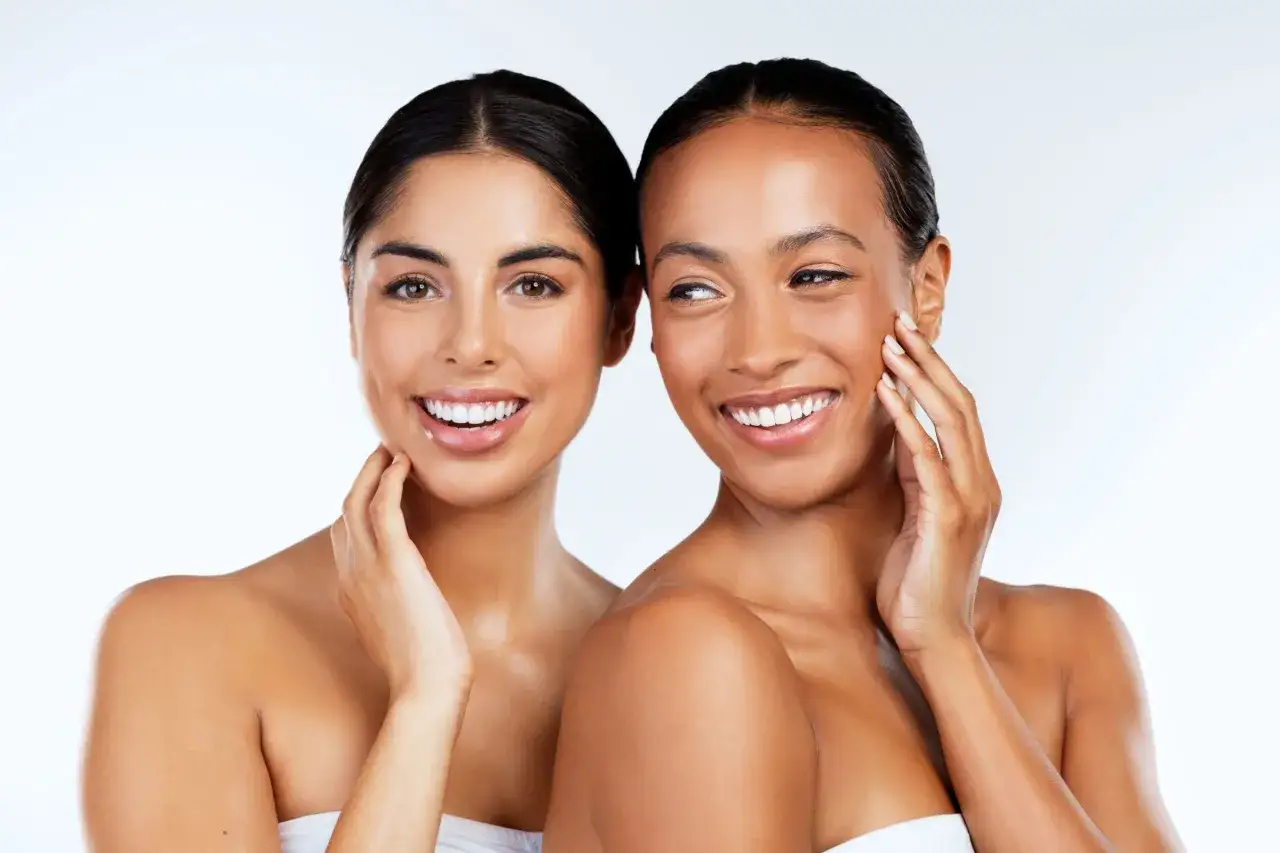 Deux femmes souriantes aux peaux &eacute;clatantes. Pour une peau douce, demandez-vous combien de gommage par semaine est id&eacute;al.