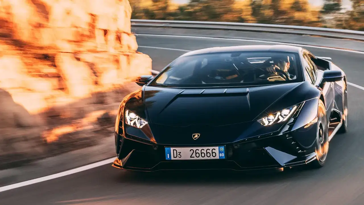 Czarny Lamborghini Huracan Tecnica pędzi po krętej drodze, oświetlony zachodzącym słońcem.