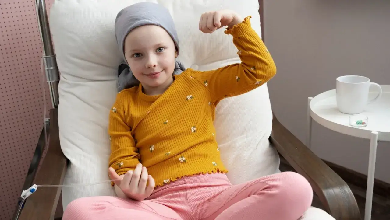 Mała wojowniczka z neuroblastomą, w żółtej bluzce, pokazuje siłę.