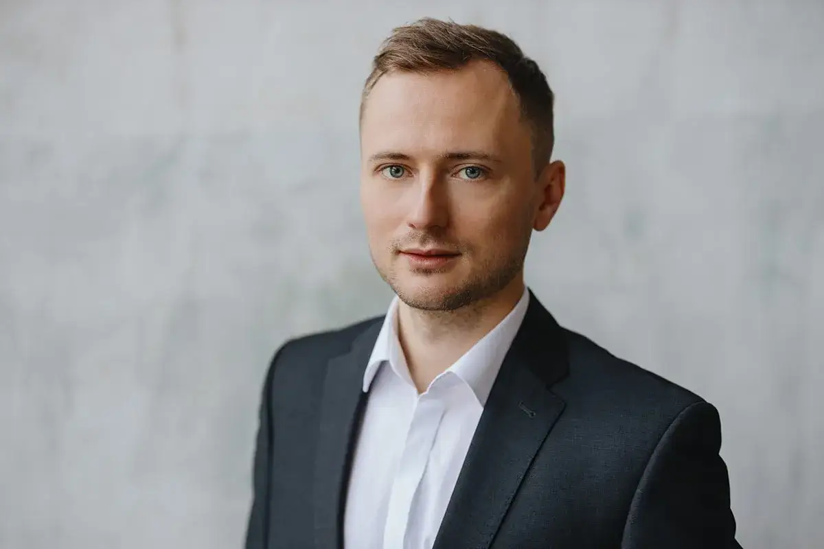 Mężczyzna w garniturze i białej koszuli, idealny przykład, jak zrobić zdjęcie biznesowe w domu.