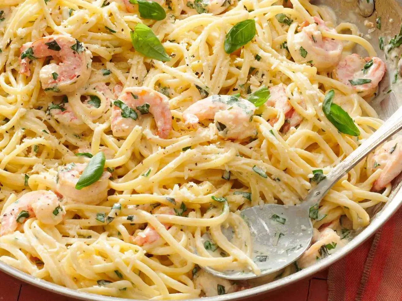 Linguine mit Garnelen in cremiger Sauce, garniert mit frischem Basilikum und Parmesan. Ein köstliches Gericht, das zum Genießen einlädt.