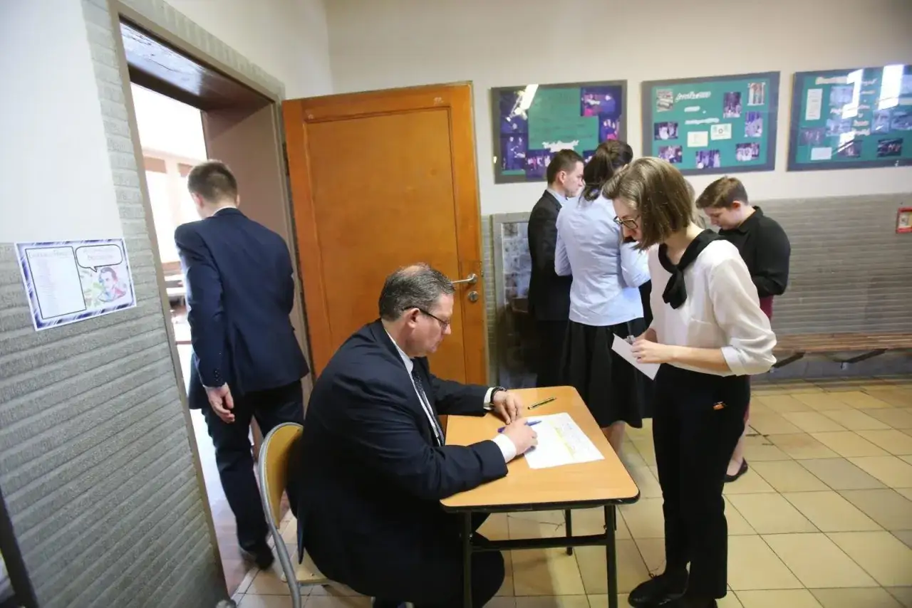 Uczniowie czekają na **maturę ustną polski**. Nauczyciel sprawdza dokumenty.