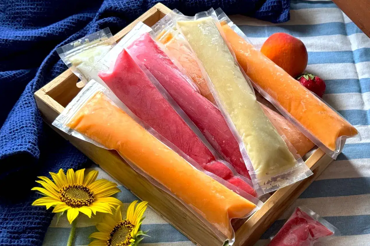 Colorati ghiaccioli senza zucchero in un vassoio di legno, con girasoli e frutta fresca.