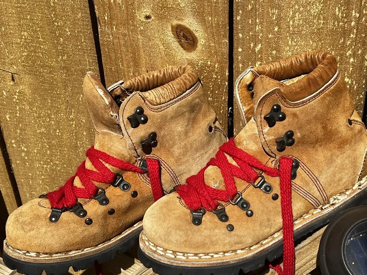Brown suede hiking boots with bright red laces. Why do hiking boots have red laces? Perhaps for visibility on the trail, or just a bold style choice for adventure.
