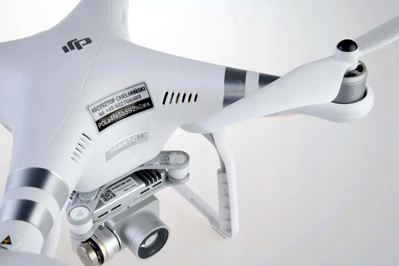 Biały dron DJI Phantom Advanced z widoczną naklejką rejestracyjną z danymi właściciela i numerem seryjnym.