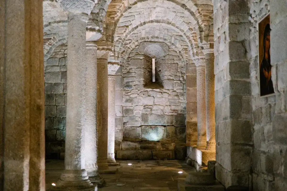 Interno dell'Abbazia di San Salvatore: colonne di pietra, archi in pietra e un'icona sacra.