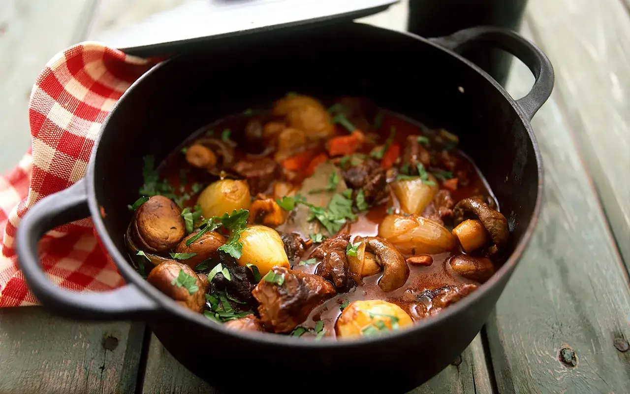 En mustig boeuf bourguignon i gjutj&auml;rnsgryta med champinjoner, l&ouml;k och &ouml;rter.