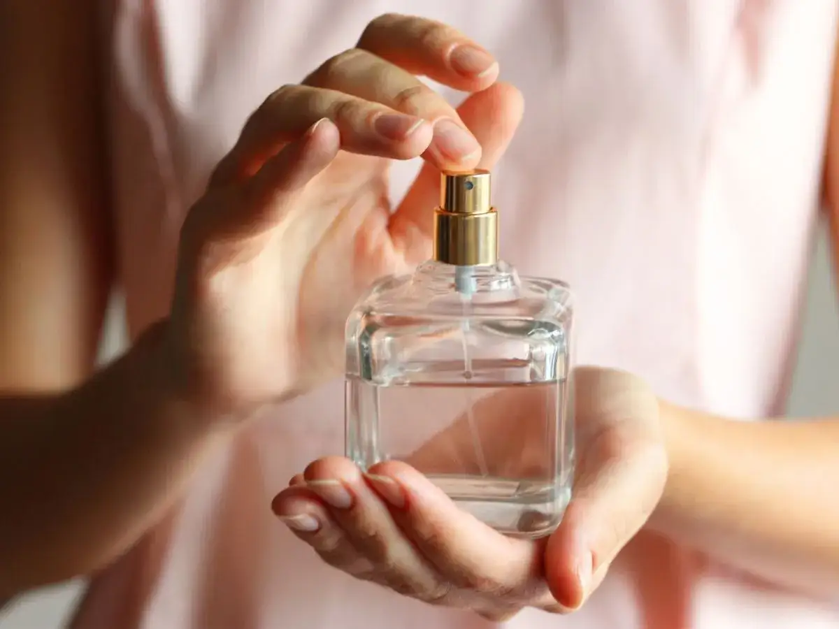 Elegancka kobieta aplikująca perfumy na nadgarstek, w luksusowej scenerii