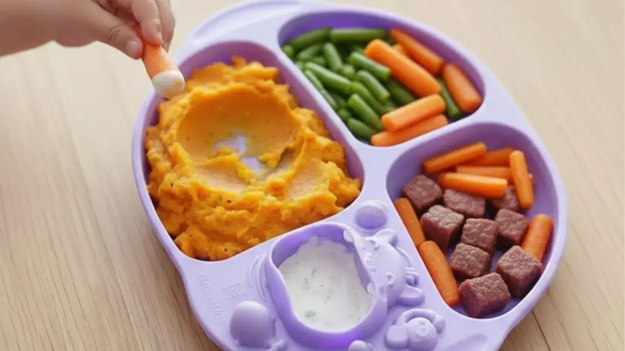 Assiette pour bébé avec purée de patate douce, haricots verts, carottes et cubes de viande, des aliments riches en fer pour une croissance saine.
