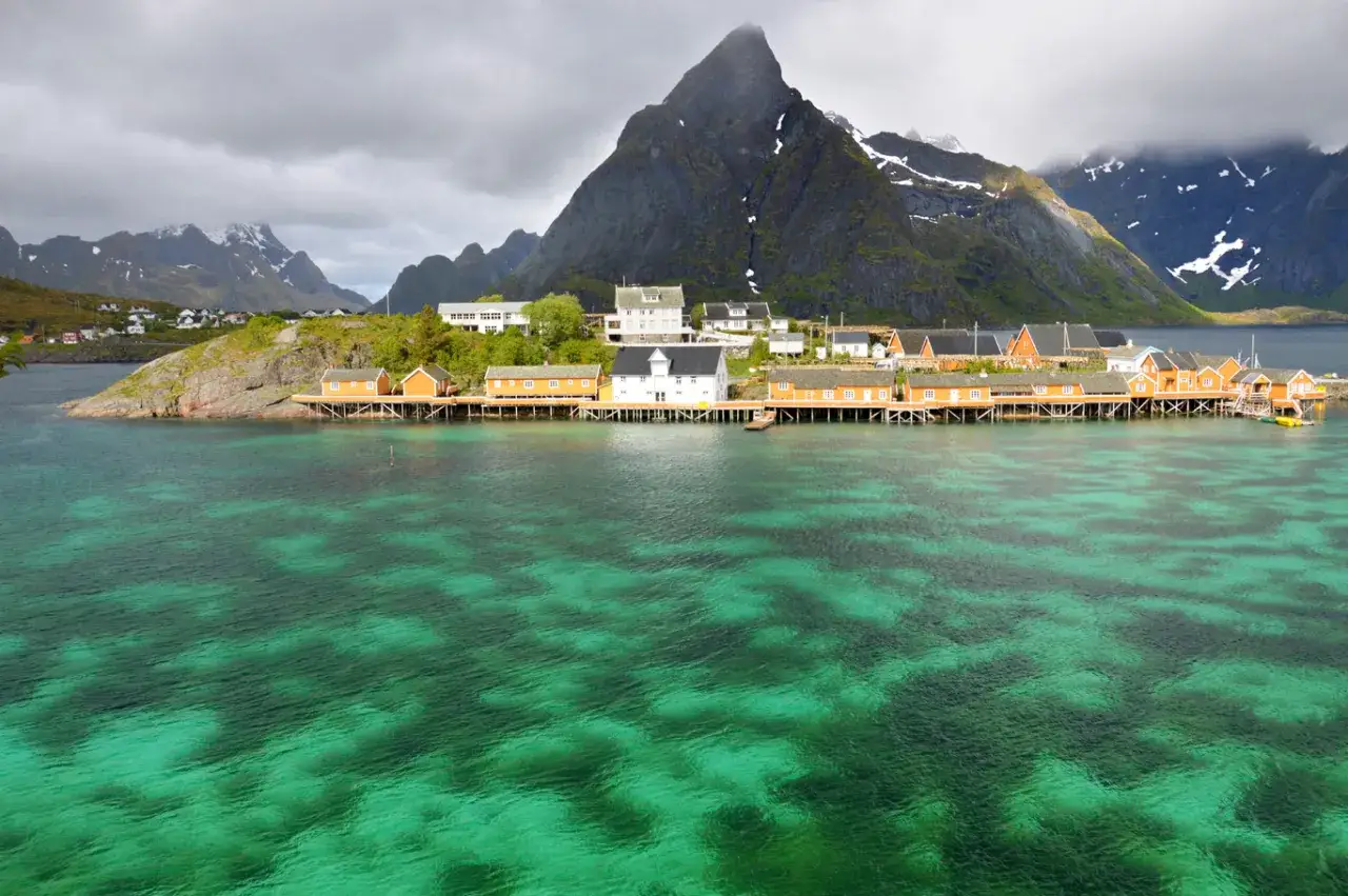 En dr&ouml;m att bila till Lofoten! R&ouml;da stugor p&aring; p&aring;lar vid turkost vatten, med dramatiska berg bakom.