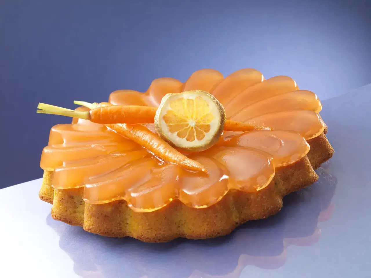 Deliziosa torta di carote con glassa arancione, decorata con carotine e una fetta di agrume.